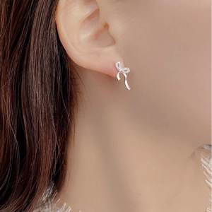 Detail of silver ribbon bow earrings with micro-pave cubic zirconia worn on ear
