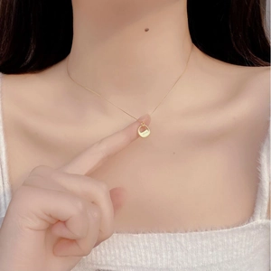 Detail of 925 silver gold plated necklace with engraved circular pendant on model