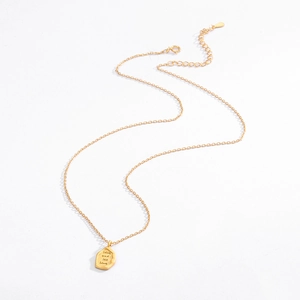 Macro shot of irregular matte gold pendant with Live and let live engraving on chain