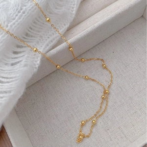 Close-up of elegant gold beaded choker chain made of S925 sterling silver on white fabric
