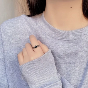 Detail of silver chain ring with black agate stone on hand over gray sweater