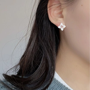 Close-up of S925 silver clover earrings with floral engraving on the earlobe