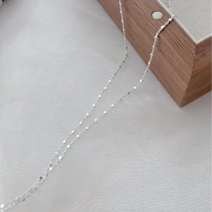 Macro shot of S925 sterling silver necklace with flat geometric discs on light fabric