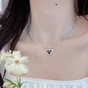 Detail of layered S925 silver necklace with heart cherry enamel pendant on model