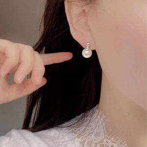 Close-up of minimalist 925 silver pearl stud earring worn on a female ear