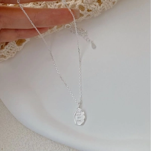 Macro shot of S925 sterling silver engraved rectangular pendant and delicate link chain