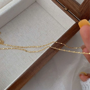 Detail of a minimalist gold S925 silver necklace featuring small geometric cubes