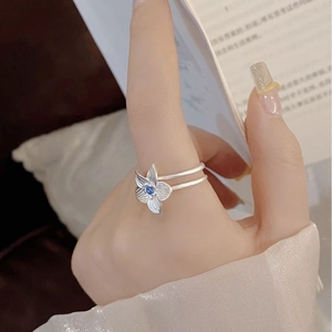 Detail of S925 silver hibiscus flower ring with blue gemstone on model hand