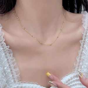 Detailed view of dainty S925 silver beaded choker chain in gold on model neck