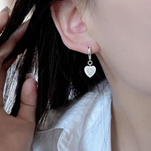 S925 sterling silver heart hoop earrings with frosted finish worn by a model
