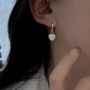 Detail shot of heart-shaped hoop earring with frosted texture worn by a model