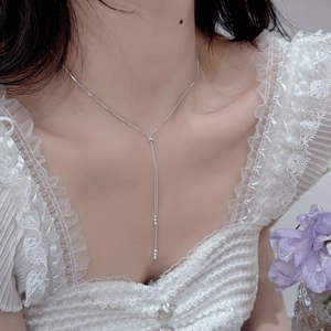 Dettaglio di una collana a Y con nappe in argento sterling S925 su una modella in pizzo
