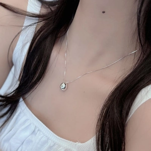 Pendentif goutte d'eau en argent poli porté au cou avec une fine chaîne minimaliste