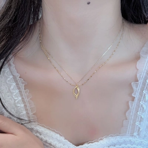 Close-up of double-layer gold necklace featuring a twisted metal pendant on a model