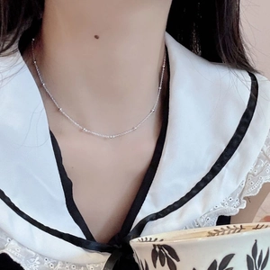 Detail view of a 925 sterling silver beaded choker necklace worn by a model in casual attire