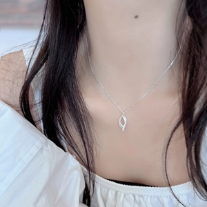 Detail of twisted oval S925 silver pendant necklace worn on a woman's collarbone