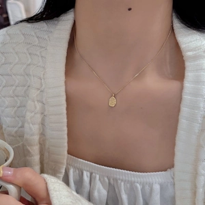 Detail of matte gold irregular pendant with custom engraving on a fine cable chain