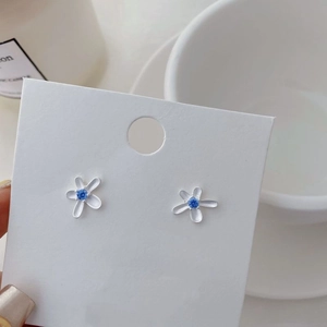 Macro shot of silver five-petal flower stud earrings with blue zircon on display