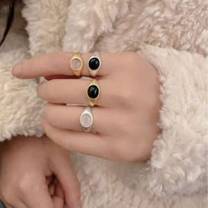 Close-up of minimalist matte gold and silver rings with black and white oval gemstones