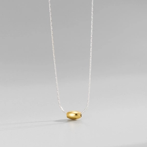 Detail of S925 sterling silver chain with a polished gold oval bead pendant