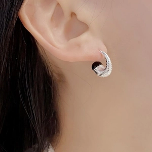 Détail macro de la boucle d'oreille spirale en argent S925 avec perle d'agate noire