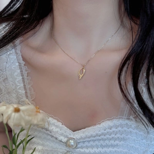 Close-up of minimalist gold geometric pendant necklace on model wearing white lace clothing