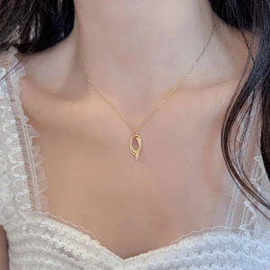 Detail of a minimalist gold twisted oval pendant necklace worn on a woman's neck