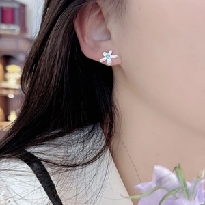 Close-up of S925 sterling silver flower stud earring with blue zircon on model ear