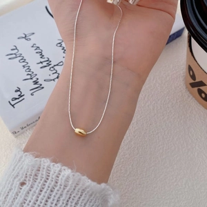 Minimalist S925 sterling silver necklace with gold bean pendant on a fine silver chain