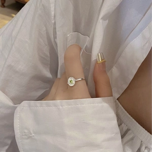 Detail of S925 silver ring featuring a green gemstone and sunburst texture on hand