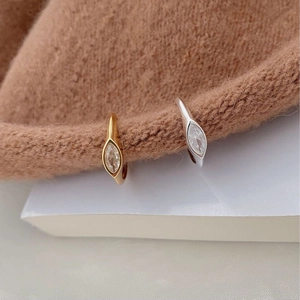 Close-up of gold and silver ear clips with marquise zircon on a knitted texture
