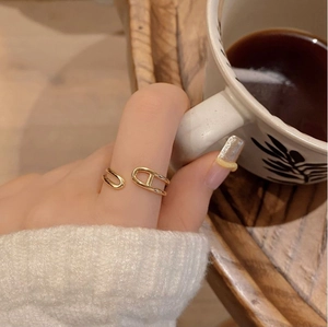 Elegant gold anchor link open ring worn on finger while holding a white coffee cup