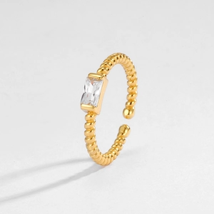 Dettaglio macro dell'anello a corda dorato con uno zircone trasparente a taglio baguette