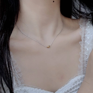 Close-up of S925 sterling silver clavicle chain with a gold olive bead on a female model