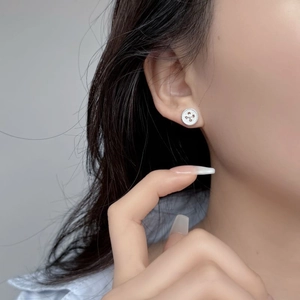 Close-up of a 925 sterling silver button earring with textured rim on a model's ear