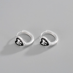 Detailed macro of S925 silver heart earrings with black enamel and bow knot design
