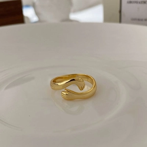 Gros plan d'une bague mains qui s'enlacent en argent s925 doré sur plat blanc