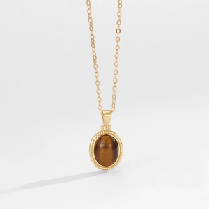 Detail of vintage oval tiger eye stone pendant with gold necklace on white backdrop