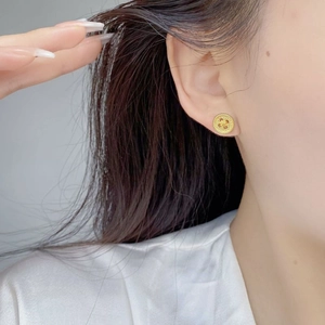 Close-up of vintage gold button stud earrings with matte texture on female ear