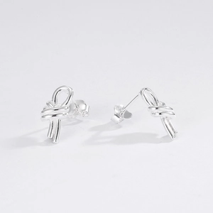 Macro shot of silver knotted stud earrings with polished double-line design and butterfly back