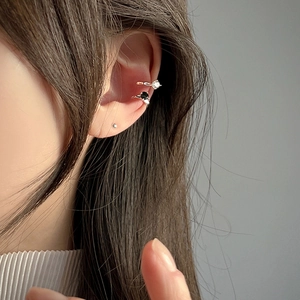 Detail of silver ear cuff set with white and black zirconias worn on the ear