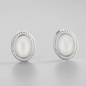 Gros plan de boucles d'oreilles ovales en nacre avec bordure torsadée en argent