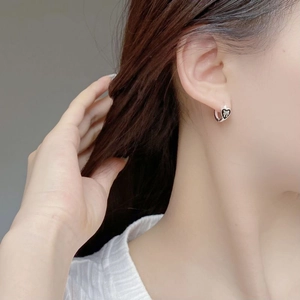 S925 sterling silver heart earrings with black enamel bow design worn by a model