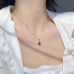 Detail of S925 silver gold necklace with oval tiger eye stone pendant on a model