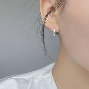 Close-up of a S925 silver hoop earring with white enamel and a rectangular zircon stone
