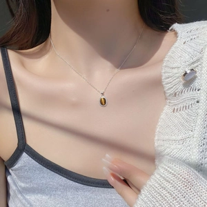 Macro shot of silver tiger eye stone pendant necklace on model with soft lighting