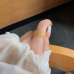 Close-up of golden vintage filigree lace hollow ring on hand with silk sleeve background