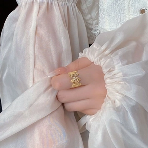 Vintage 925 silver lace hollow ring in gold finish worn on hand with silk background