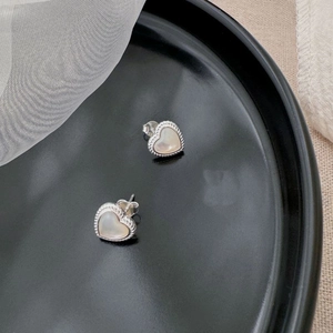 Macro detail of S925 sterling silver heart studs with elegant white mother of pearl inlay