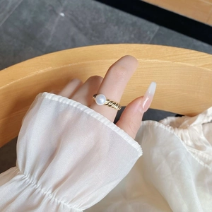 Close-up of elegant S925 sterling silver twist ring with a lustrous natural pearl on finger